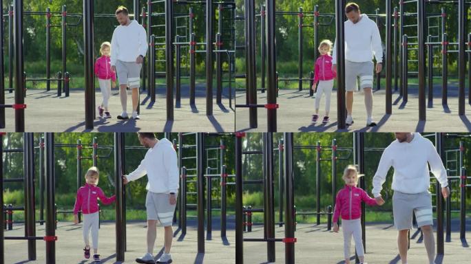 快乐的爸爸和小女儿在户外健身操场散步