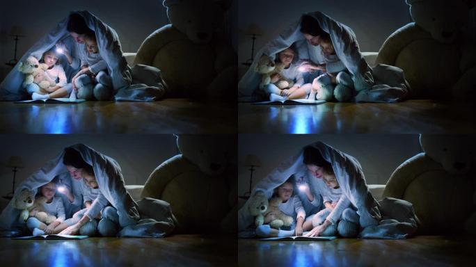 《年轻母亲的慢动作》正在用毯子下的火炬照亮黑暗中的小女儿，向她的小女儿读晚安故事。