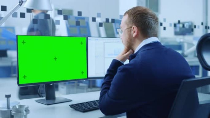 工业工程师在个人计算机上工作，两台显示器显示绿屏显示和cad软件，并测试了3D Eco引擎。现代工厂