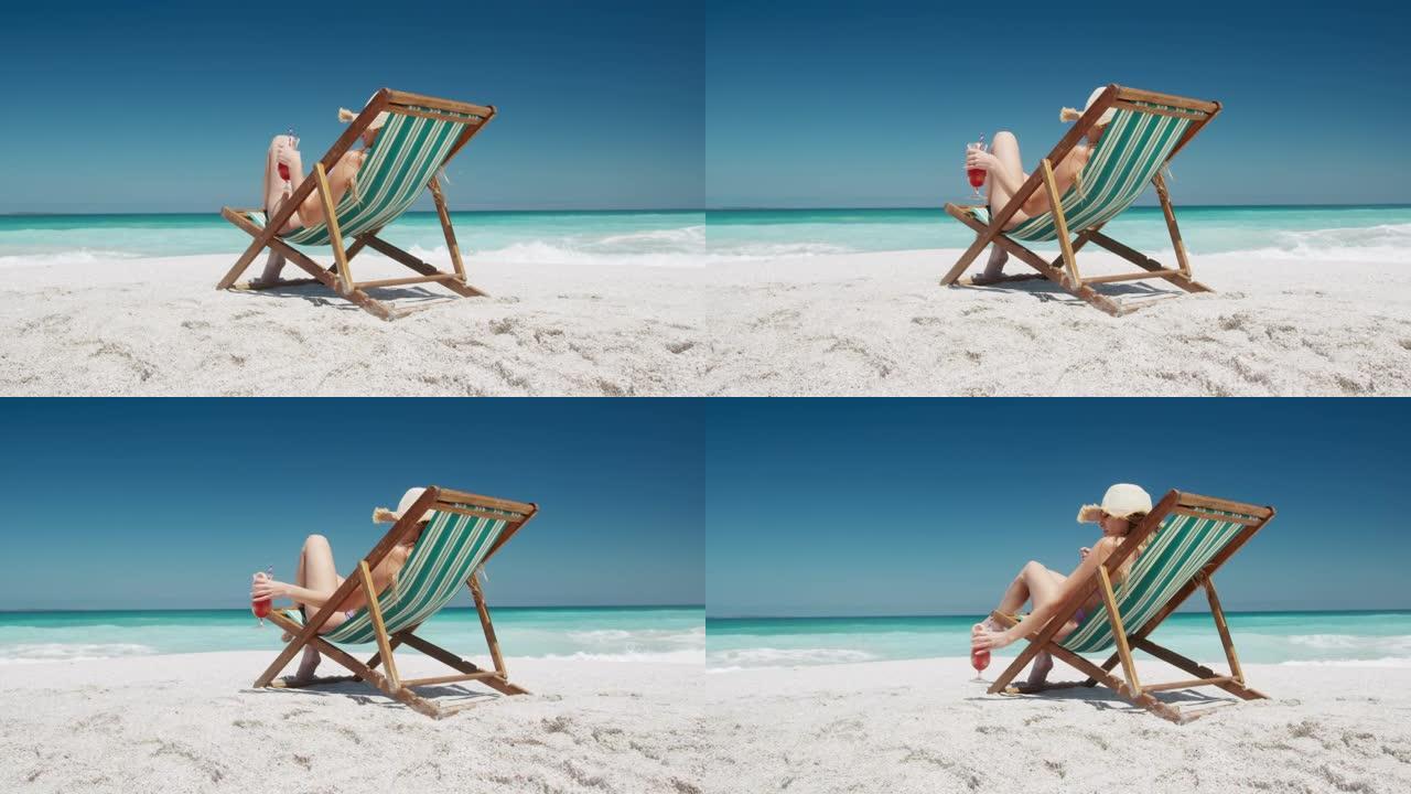 女人在沙滩上的躺椅上喝鸡尾酒