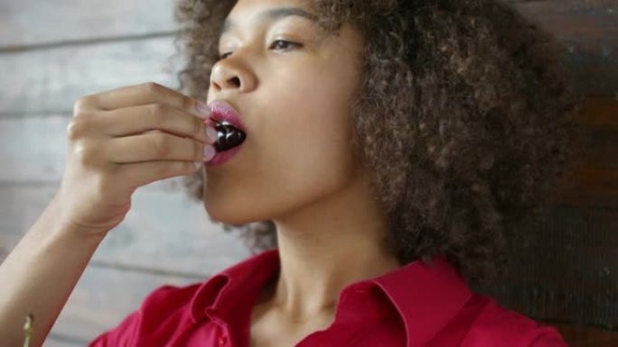 优雅的年轻黑人妇女吃樱桃