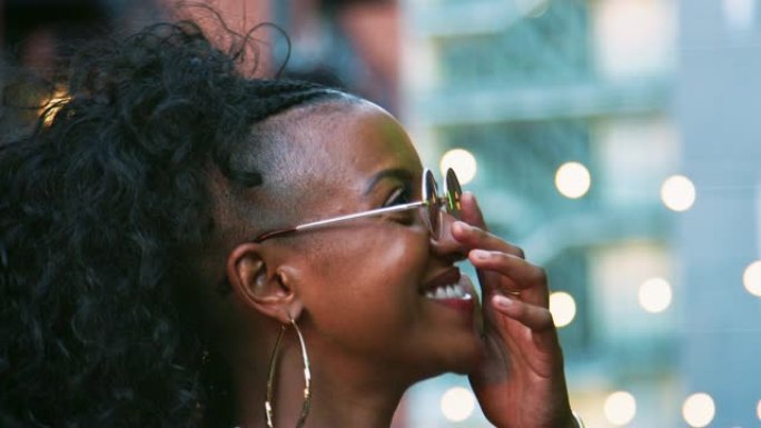 时尚的年轻黑人女性戴着太阳镜四处张望，头部拍摄，背景中的波克灯