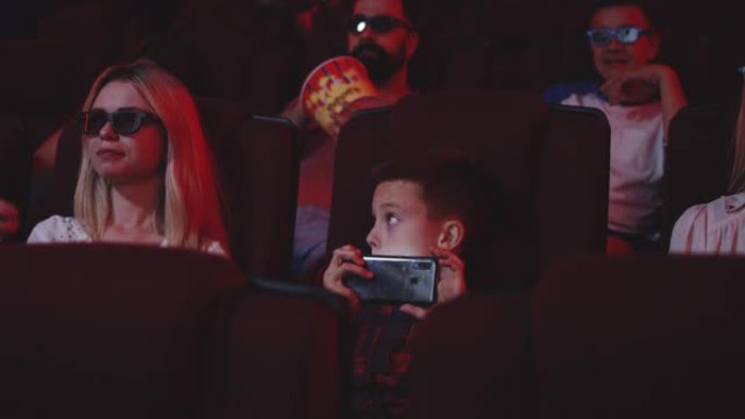 男孩用智能手机在电影院盗版电影