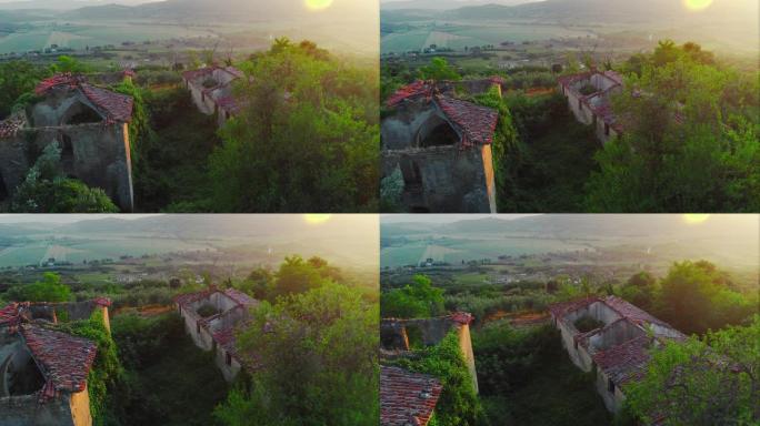 空中电影无人机可以看到有山和森林的乡村。相机在一栋废弃的旧房子旁边拍照。雾蒙蒙的阳光明媚的早晨，在一