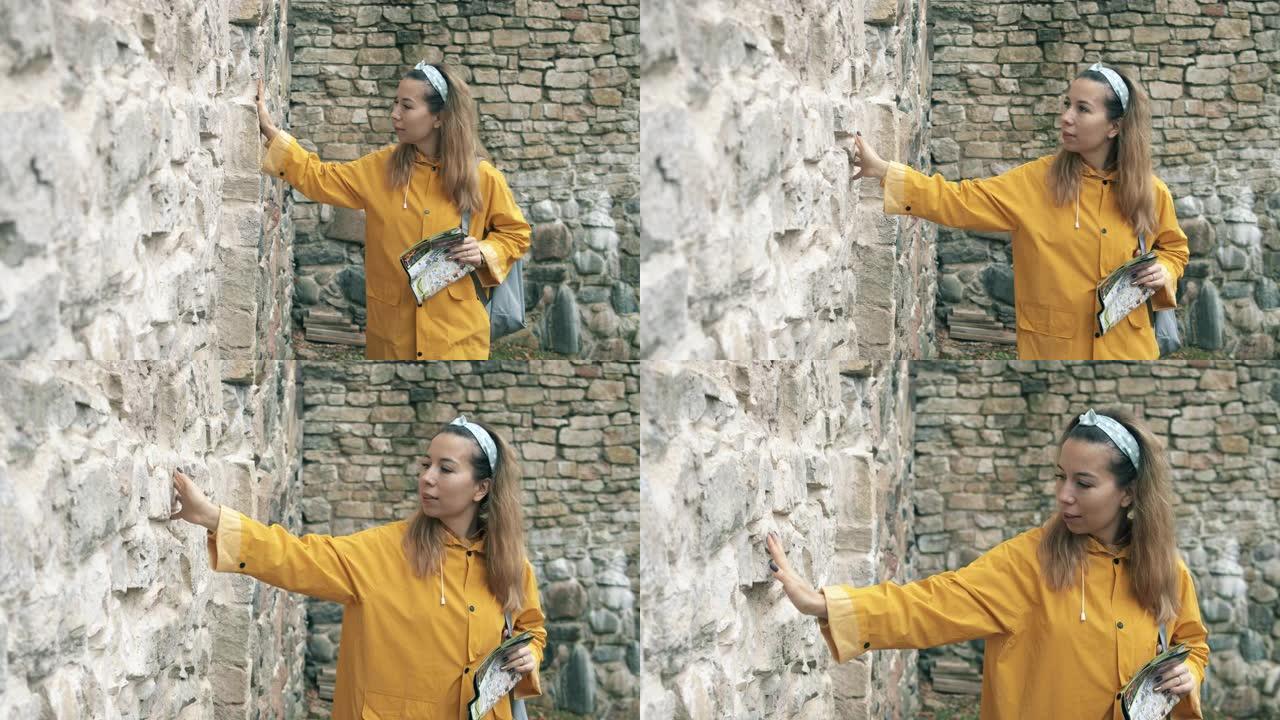 女游客正在触摸一座古老的砖墙