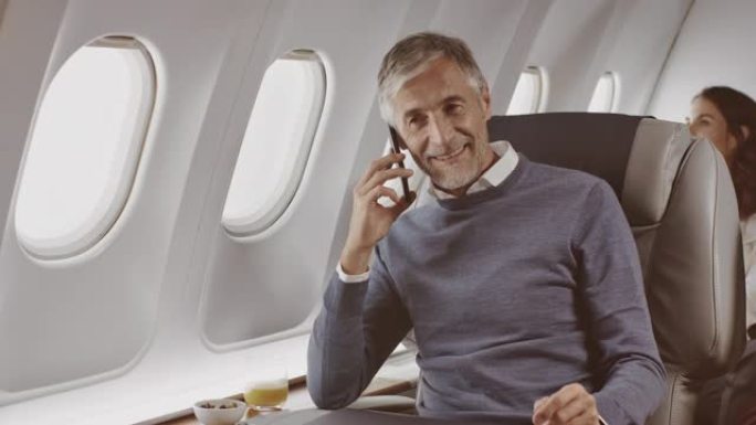 在飞机上智能手机上聊天的商人