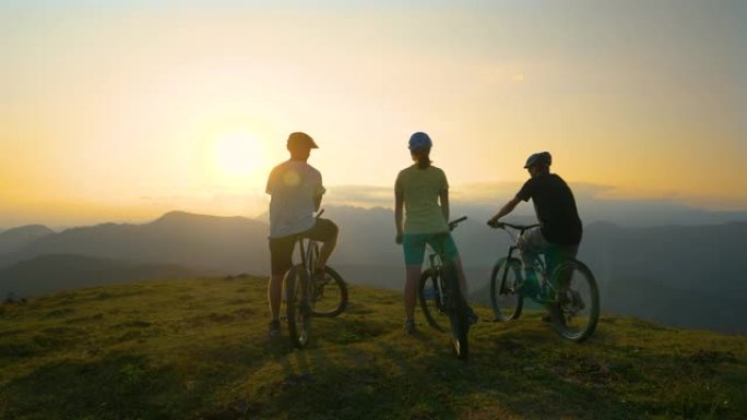 镜头耀斑: 无法识别的运动型游客在自行车上休息并观察日出