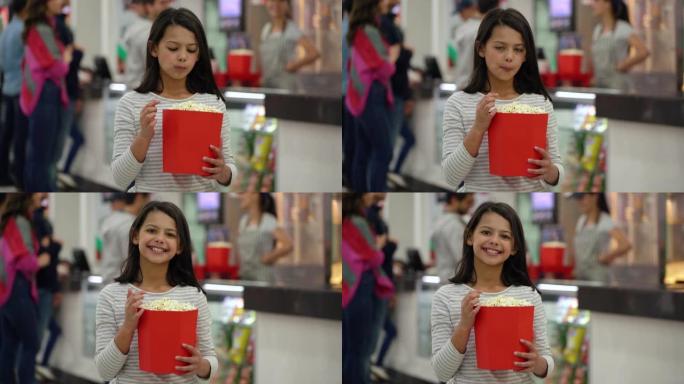 美丽的小女孩吃爆米花，然后在电影院对着镜头微笑
