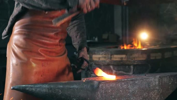铁匠铺工人正在用锤子敲打加热的金属