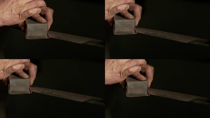 特写: 无法辨认的刀片史密斯手动磨尖了一把新锻造的刀。
