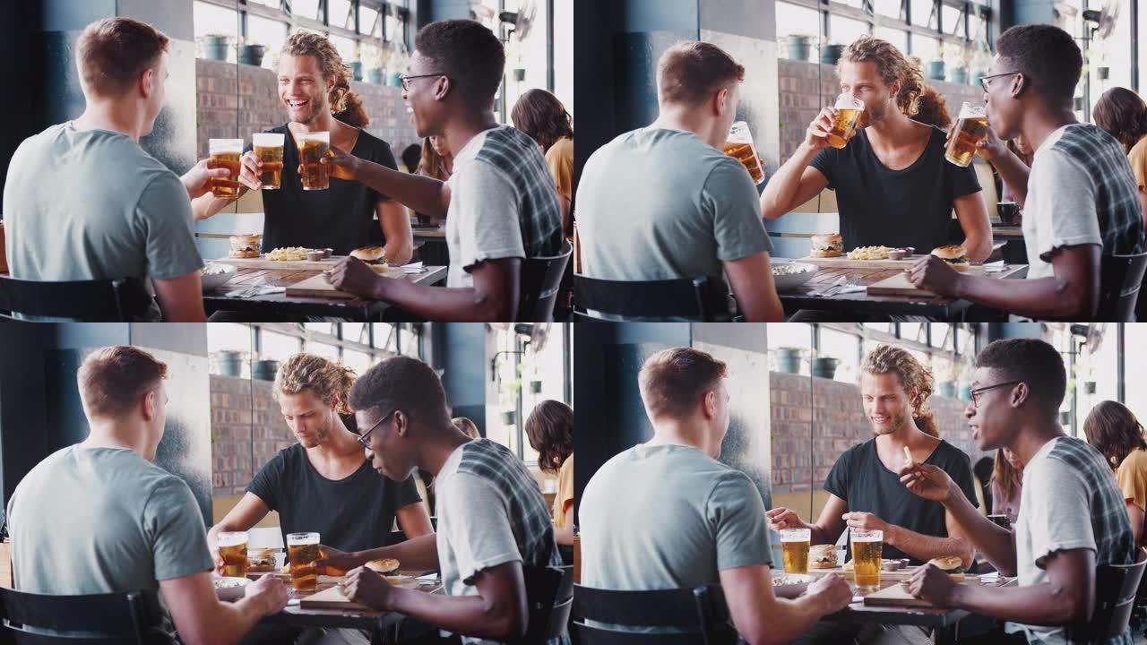 一群年轻的男性朋友在餐厅酒吧见面时用啤酒敬酒-慢动作拍摄