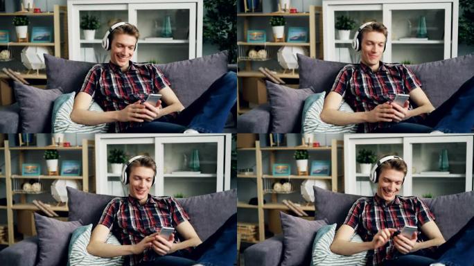 戴着耳机的快乐年轻人正在家里听音乐和使用智能手机