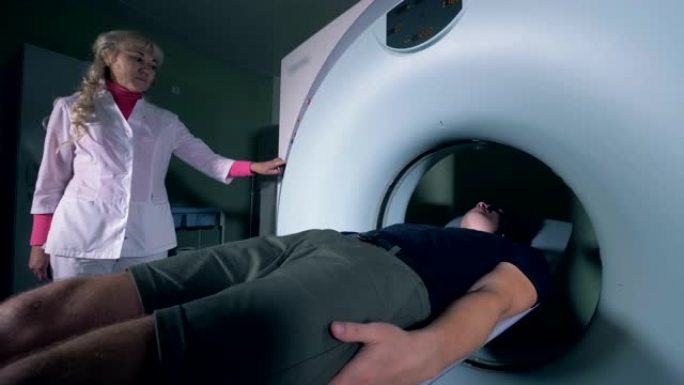女医务人员正在控制患者从MRI机器中移出的过程