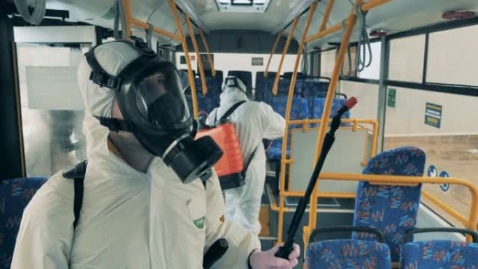 三名工人对公共汽车进行消毒以防止冠状病毒传播。