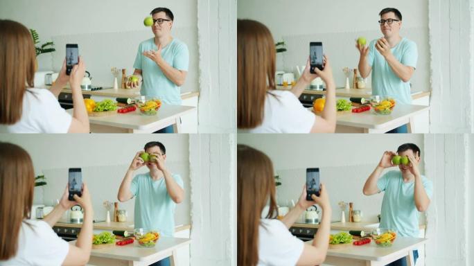 男人在玩苹果，然后在女人拍照时摆姿势为智能手机相机摆姿势
