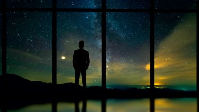 站在星空背景上的全景窗口附近的男性。时间流逝