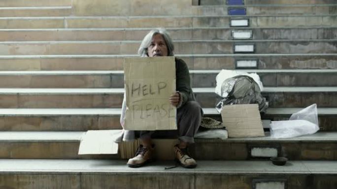 坐在人行道上的无家可归的老人的平移。