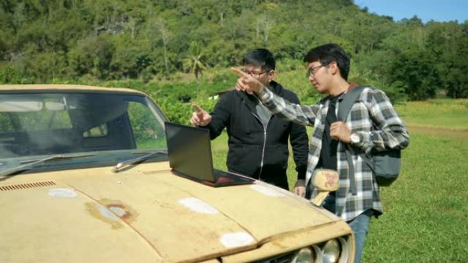 两名亚裔男子在皮卡车上使用笔记本电脑