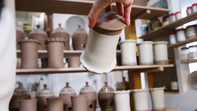 陶瓷工作室中男性陶工在粘土花瓶上施釉的特写