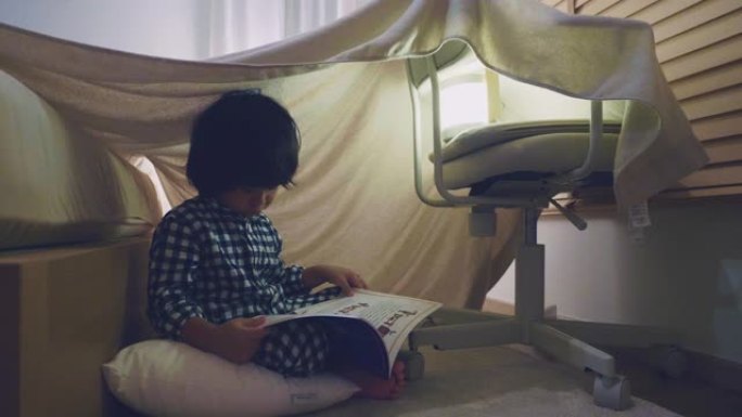 小男孩在家里的小帐篷里看书