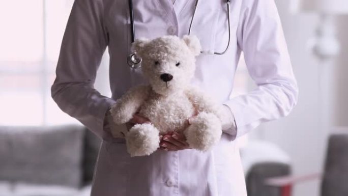 女子儿科医生拿着泰迪熊玩具，特写镜头
