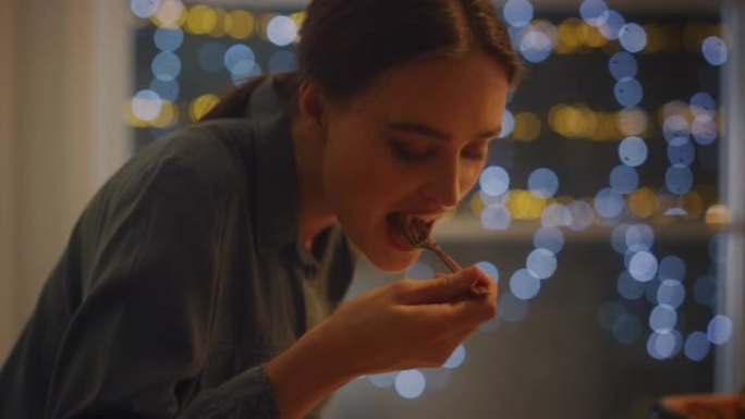 一个美丽的年轻女子在盘子上吃美味的意大利面的肖像。餐厅里专业烹制的意大利面食或家里浪漫的晚餐。舒适的