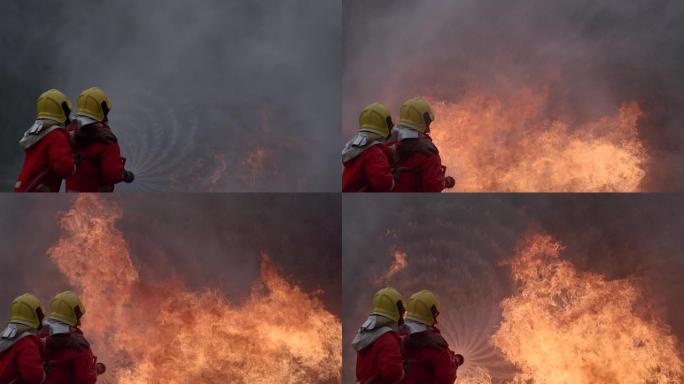 在燃烧的建筑物中值班的坚强勇敢的消防员。两名消防员在消防期间用软管和水灭火