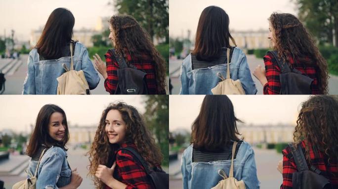 迷人女孩的慢动作朋友带着背包一起散步，聊天，然后看着相机，微笑着在美丽的城市享受假期。