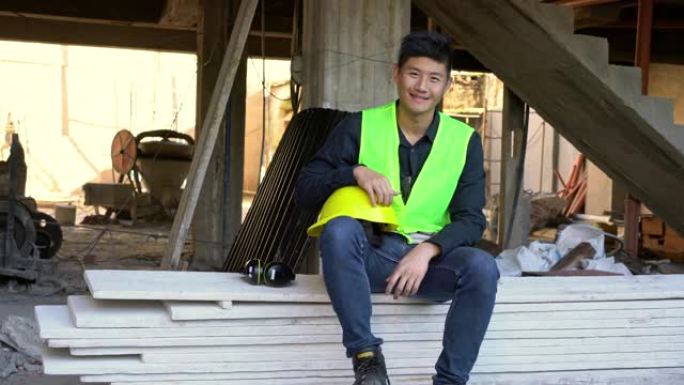 微笑的年轻建筑承包商坐在木板上