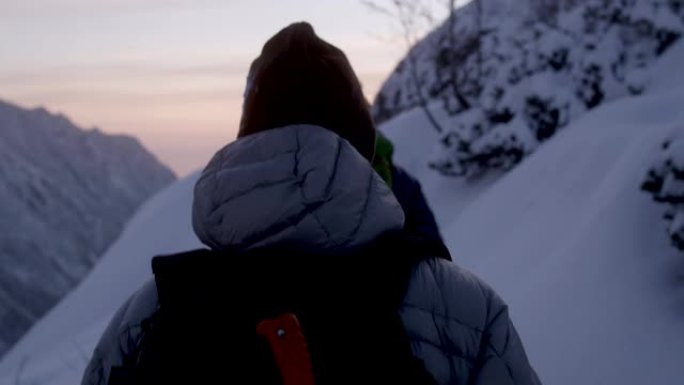 冬季山地探险。小路上的年轻夫妇。日落