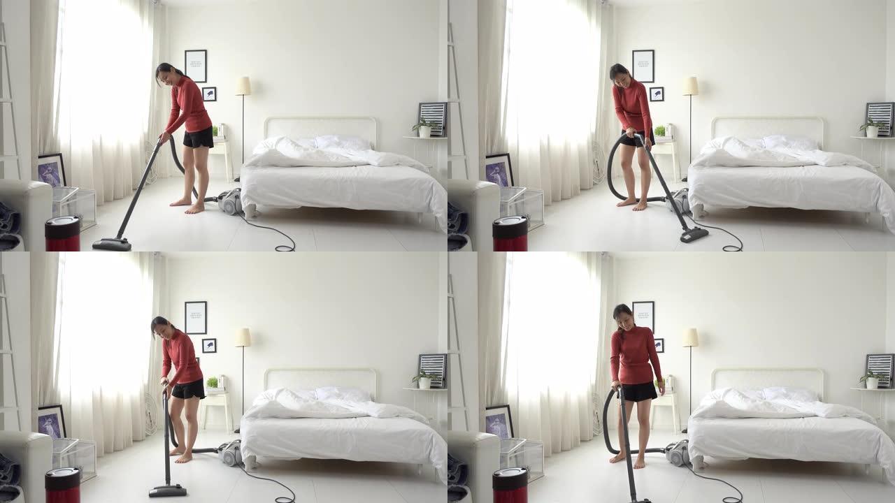 穿着休闲衬衫和短裤的年轻亚洲女子在她的房间里进行真空清洁