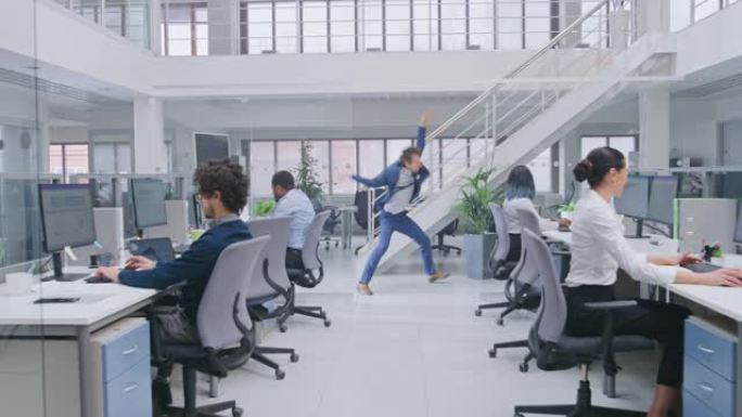 穿着西装打着领带的年轻开朗英俊的商务经理在办公室里疯狂地跳舞。在现代开放式办公室中，多元化且积极进取
