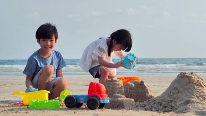 男孩和女孩在海滩上玩沙箱。快乐的家庭在海滩上享受暑假。假期概念。假期-iStock