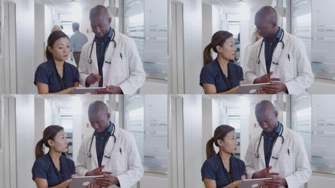 医生和护士在繁忙的医院走廊上通过数字平板电脑进行咨询