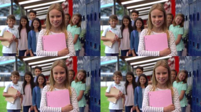 学校里漂亮的女孩看起来很开心，对着镜头微笑，而同学们站在后台