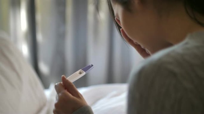 悲伤的亚洲妇女怀孕使用怀孕测试