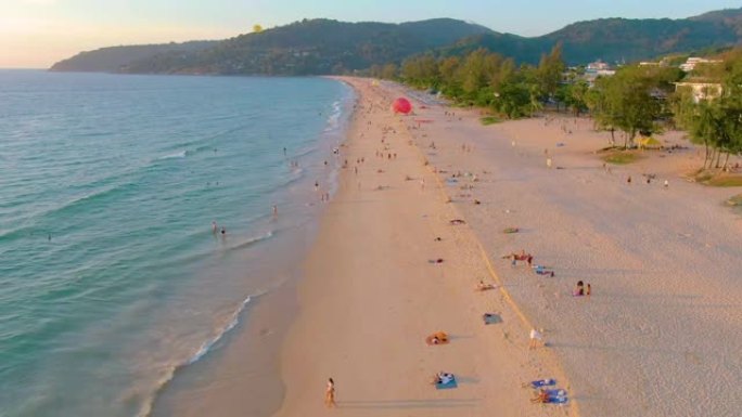 泰国普吉岛-2020年3月15日: 卡隆海滩日落，人们在海中游泳，享受日光浴，度假海滩。由于检疫新型