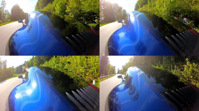 蓝色跑车在空旷的蜿蜒乡间小路上行驶，被阳光照亮
