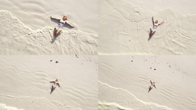 空中海浪溅到一个躺在沙滩上的快乐女人身上