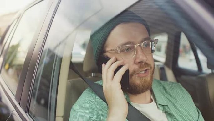 坐在汽车乘客座位上的英俊年轻人打了个电话，与客户，客户和商业伙伴交谈。从车外拍摄的摄像机。