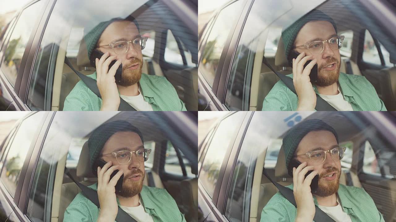 坐在汽车乘客座位上的英俊年轻人打了个电话，与客户，客户和商业伙伴交谈。从车外拍摄的摄像机。