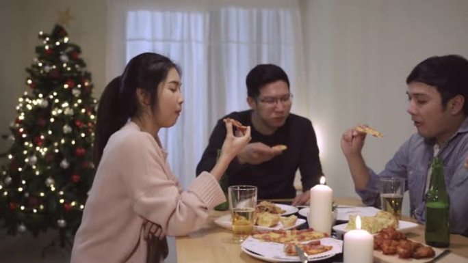 一群亚洲朋友在圣诞晚宴上玩得开心。快乐的泰国人在家里的聚会上一起吃披萨。慢动作场景