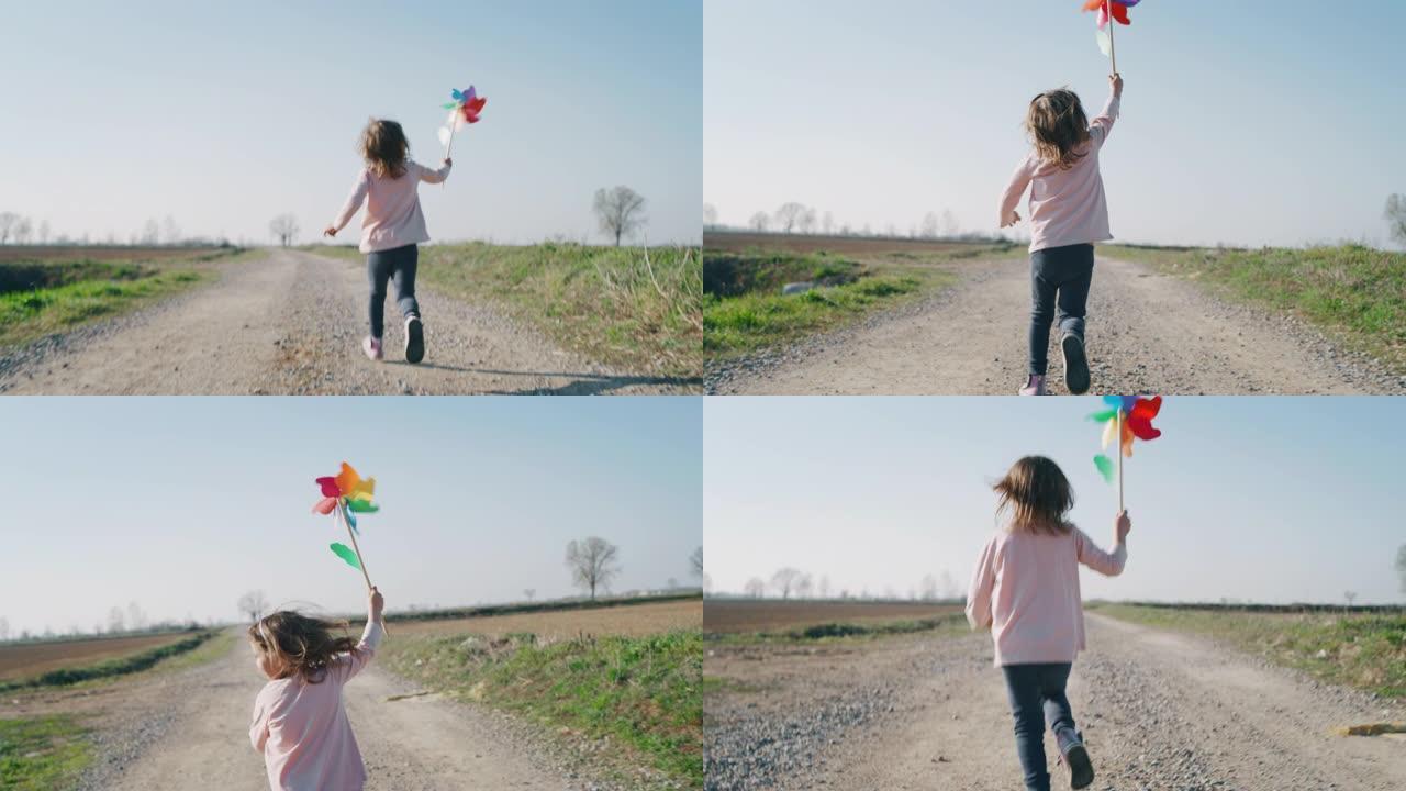 可爱的小女孩无忧无虑地奔跑，用彩色针轮玩乐的真实照片