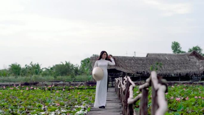 4k镜头越南美女在大莲花湖的木桥上行走和呼吸新鲜空气的场景，越南，亚洲或东南亚旅行概念