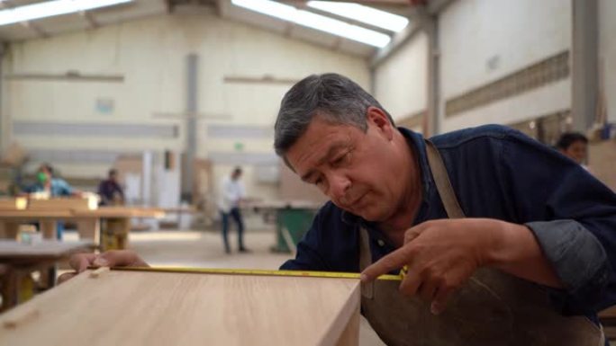 专注的男性木匠用卷尺测量木箱