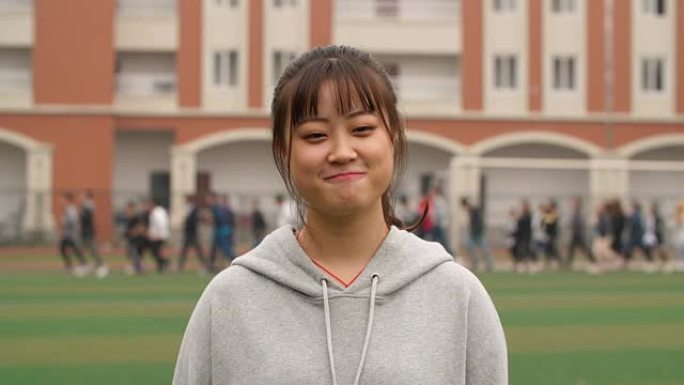年轻的亚洲女孩在校园里对着镜头微笑的肖像