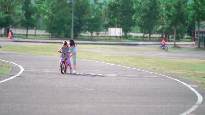 孙子和祖母正在学习在公园里骑车