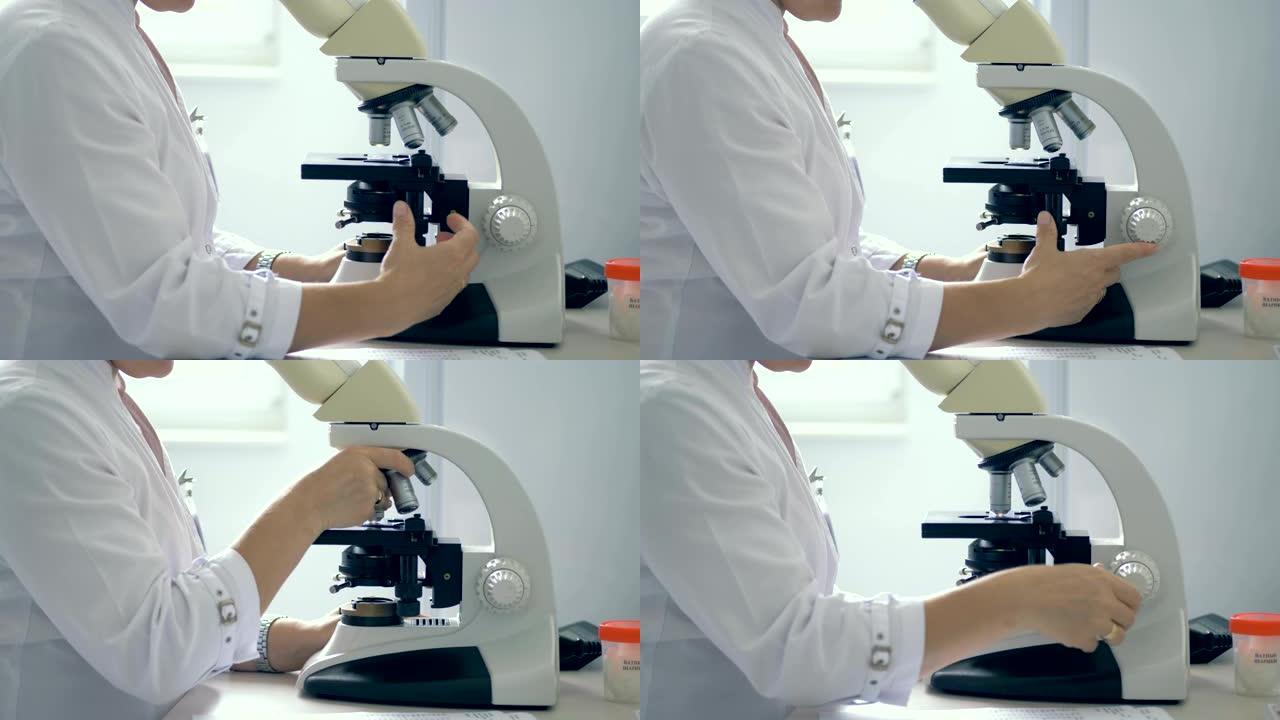 使用显微镜的实验室工作人员。一个人在实验室用显微镜工作。