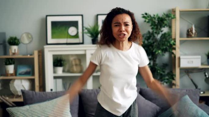 愤怒的非洲裔美国妇女在现代公寓里大喊大叫并打手势表达负面情绪的肖像。人的感情和人的概念。