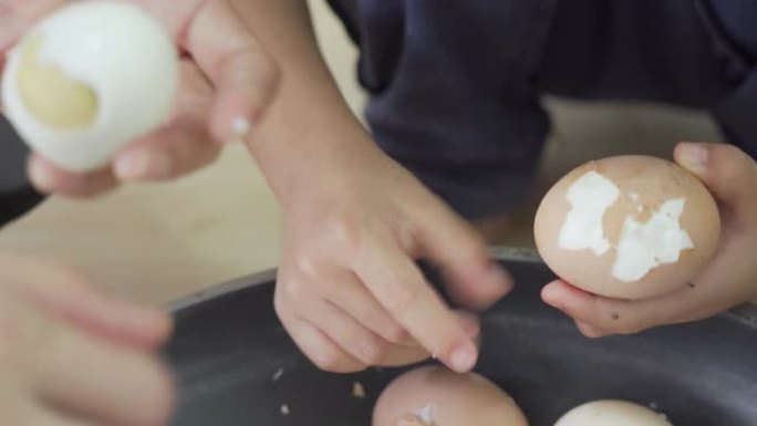女性和孩子的手剥煮鸡蛋。